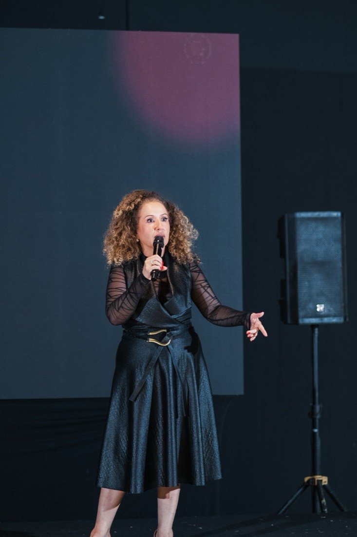 Flávia no palco, falando ao microfone